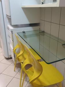 uma cadeira amarela sentada ao lado de uma mesa de vidro em Apartamento Caruaru em Caruaru