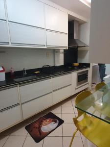 a kitchen with white cabinets and a sink and a table at Apartamento Caruaru in Caruaru