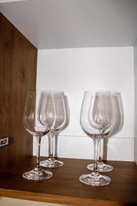 four empty wine glasses sitting on a wooden shelf at Departamento Exclusivo Enfrente de Arena Monterrey in Monterrey