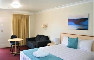 um quarto de hotel com uma cama e uma cadeira em Club Motel Armidale em Armidale