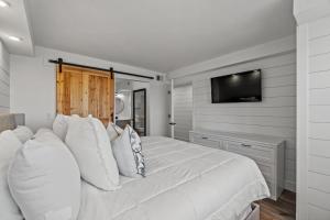 a bedroom with a white bed with a television on the wall at The Summit 803 - Luxury Beach Resort Condo - Beachfront - Incredible Views - BEACH CHAIRS AND SUNSHADE Provided In Condo in Panama City Beach