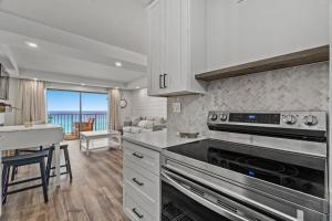 a kitchen with a stove top oven next to a living room at The Summit 803 - Luxury Beach Resort Condo - Beachfront - Incredible Views - BEACH CHAIRS AND SUNSHADE Provided In Condo in Panama City Beach