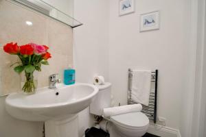 a bathroom with a sink and a toilet and a vase of flowers at Swan Studio Four - Coventry in Coventry