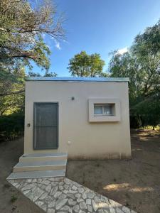 a small white building with a window and trees at Casa con Piscina y Mirador privado en San Marcos Sierras in San Marcos Sierras