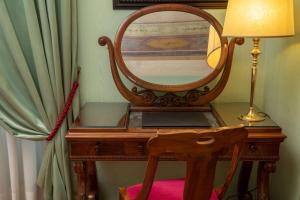 a wooden desk with a mirror and a lamp at Hotel Canada, BW Premier Collection in Rome