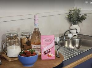 a bottle of wine and a bowl of strawberries next to a sink at Daylesford FROG HOLLOW ESTATE- The Retreat in Daylesford
