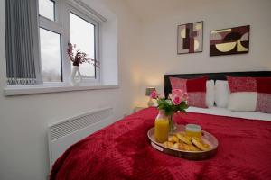 a bedroom with a red bed with a tray of food on it at Swan Studio Five - Coventry in Coventry