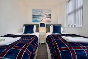 1 dormitorio con 2 camas y mantas azules y rojas en Swan Studio Six - Coventry, en Coventry