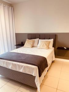 una camera da letto con un grande letto con lenzuola e cuscini bianchi di Loft's Freitag a Joinville