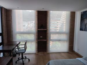 Aparta Suite - Centro Internacional - Mitika في بوغوتا: غرفة نوم مع مكتب ونوفذين كبيرتين