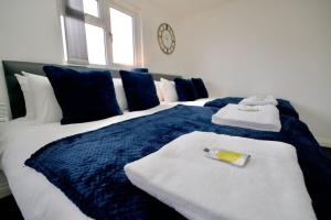 a blue and white bed with towels and a clock at Swan Studio Eight - Coventry in Coventry