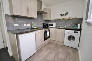 a kitchen with white cabinets and a washer and dryer at Swan Studio Eight - Coventry in Coventry