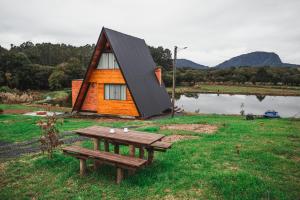 een klein huis met een picknicktafel en een bank bij Chalé romântico com banheira de hidromassagem e lareira in Bom Retiro