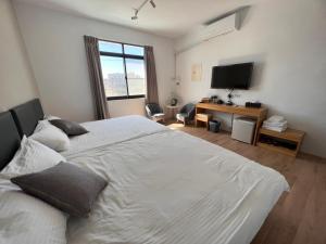 a bedroom with a large white bed and a television at Chia Lung Gold Coast Homestay in Hunei