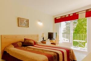 a bedroom with a bed and a large window at Auberge de la Rivière Saguenay in La Baie