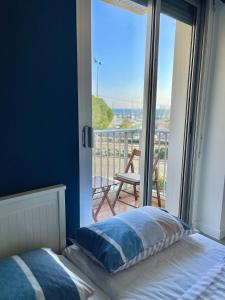 Schlafzimmer mit einem Bett und Blick auf einen Balkon in der Unterkunft Appartement bord de mer avec piscine in Saint-Laurent-du-Var