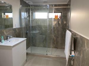 a bathroom with a glass shower and a sink at 3 Bedroom Holiday Apartment Peninsula Park in Auckland