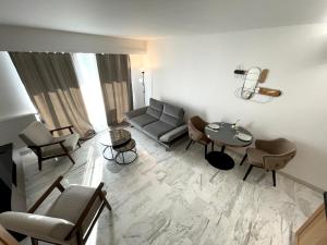 ein Wohnzimmer mit einem Sofa, einem Tisch und Stühlen in der Unterkunft Appartement bord de mer avec piscine in Saint-Laurent-du-Var