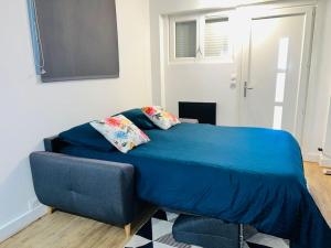 un letto blu con un divano in una camera di Superbe studio avec entrée et jardin privés à moins de 15 minutes de Paris a Bagneux
