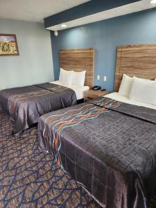 a hotel room with two beds and blue walls at Travelodge by Wyndham Barstow in Barstow
