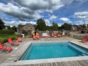 a swimming pool on a deck with red chairs around it at Spacious Holiday Home La Roche en Ardenne with Pool in Beausaint