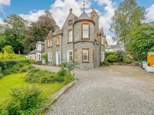 an old stone house with a gravel driveway at Meadow House Apartment in Moffat