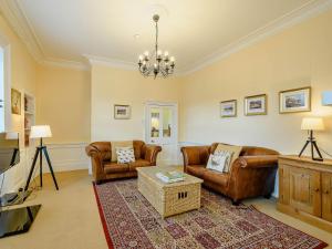 a living room with leather furniture and a chandelier at Meadow House Apartment in Moffat