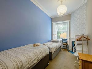 two beds in a bedroom with a teddy bear laying on top at Meadow House Apartment in Moffat