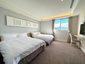 una camera d'albergo con due letti e una finestra di Caffir Garden Hotel a Jiji