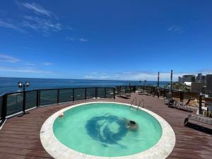 una piscina en una terraza con el océano en el fondo en Flat Píer Sul Ondina, en Salvador