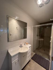ein weißes Bad mit einem Waschbecken und einer Dusche in der Unterkunft Studio at the Back of Mount Taylor in Lyons
