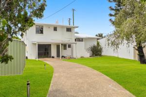 a white house with a green yard and a driveway at Coorumbong 14 in Mooloolaba