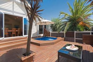 a deck with a pool and a palm tree at KaniCoast in Sorrento