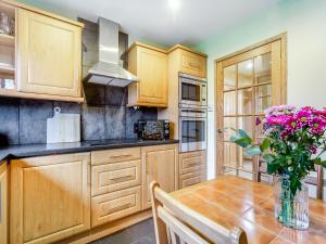 a kitchen with wooden cabinets and a table with flowers at Dorrey View Cottage - Uk39010 in Halkirk