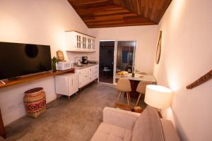 a kitchen and living room with a couch and a table at Alma Iguassu I Chalés com Banheira & Jardins in Foz do Iguaçu