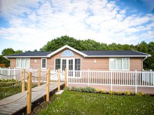 ein Haus mit einem weißen Zaun und einem Haus in der Unterkunft Aspen Lodge in Willington