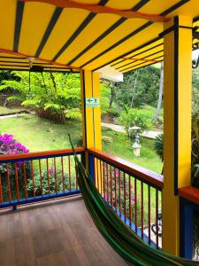 a hammock on a porch with a view of a garden at Hotel Hacienda San Isidro in Belén de Umbría