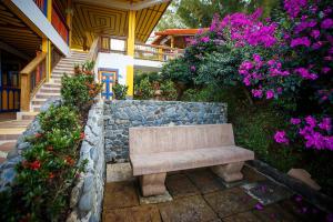 a bench sitting on a stone wall next to flowers at Hotel Hacienda San Isidro in Belén de Umbría