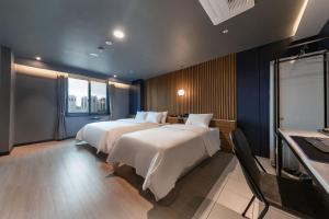 a hotel room with two beds and a window at Brown Dot Hotel Seosan in Seosan