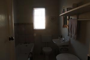 a small bathroom with a toilet and a sink at Abbastanza Self-catering in Loeriesfontein