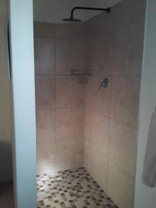 a bathroom with a shower with a tiled floor at Abbastanza Self-catering in Loeriesfontein