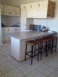 a kitchen with a counter and some stools in it at Abbastanza Self-catering in Loeriesfontein