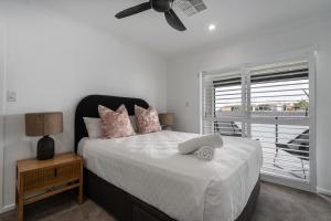 a bedroom with a bed and a window with a ceiling fan at Nimolanca - 3 Bedroom Partial Ocean View in Caloundra
