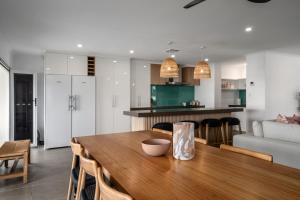 a kitchen and dining room with a wooden table and chairs at Nimolanca - 3 Bedroom Partial Ocean View in Caloundra +4 photos