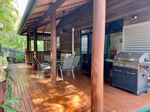 a wooden deck with a grill and a table and chairs at Beach house, Pet friendly large secure yard, Adjacent to beach in Buddina