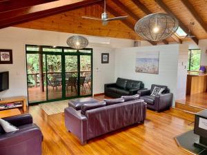 a large living room with leather couches and a television at Beach house, Pet friendly large secure yard, Adjacent to beach in Buddina