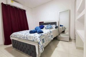 1 dormitorio con 2 camas con almohadas azules y espejo en COZY, Apartamento a solo 10 minutos Caminando a Playa Dormida, con Piscina y Parqueadero., en Santa Marta