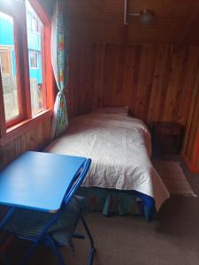 1 dormitorio con 1 cama, mesa y sillas en Esencia Chilota, en Ancud