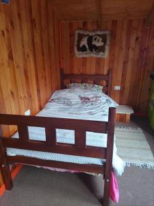 Cama de madera en habitación con paredes de madera en Esencia Chilota, en Ancud