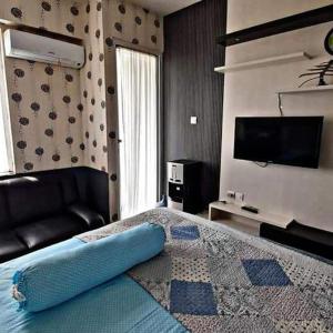 um quarto com uma cama, um sofá e uma televisão em Vin's Room at Vivo Apartemen em Seturan